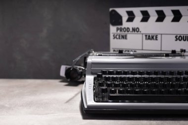 vintage retro typewriter, film camera and movie clapper board at table near wall background, abstract retro writer concept
