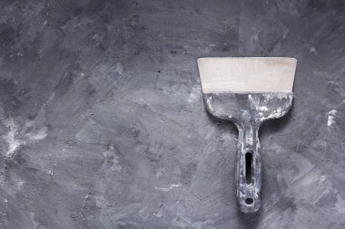 putty knife at painted surface background, wall putty or stone texture