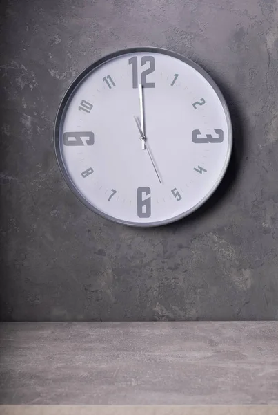 twelve o\'clock at wall clock with concrete background, grey texture surface