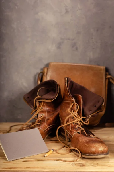 木制桌旁的老式旅行靴 靠近混凝土墙底纹理表面 — 图库照片