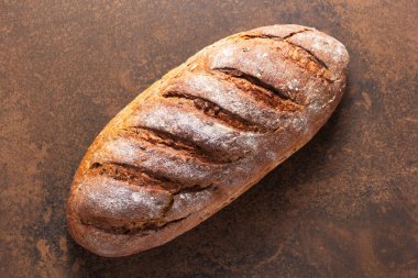 Masada bir somun taze ekmek. Kaya gibi doğal arkaplan dokusunda fırın yemekleri. Düz üst görünüm