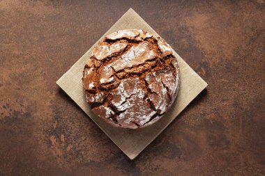 Masadaki peçeteye bir somun taze ekmek. Taştan arkaplan dokusunda fırın yemekleri. Düz üst görünüm