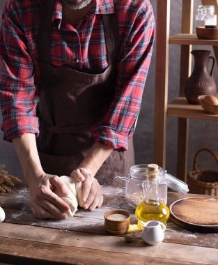 Fırıncı adam hamur yoğurur veya hamur ve fırın malzemeleri yapar. Masada ev yapımı ekmek pişirir. Duvar arkaplanı dokusu yakınında fırın kavramı