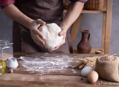 Hamur yoğuran fırıncı adam ve masada ev yapımı ekmek pişirmek için fırın malzemeleri. Duvar arkaplanı dokusu yakınında fırın kavramı