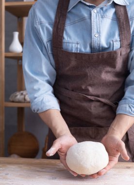 Fırıncı adam hamur yoğurur veya hamur ve fırın malzemeleri yapar Rafta ev yapımı ekmek pişirir. Duvar arkaplanı dokusu yakınında fırın kavramı