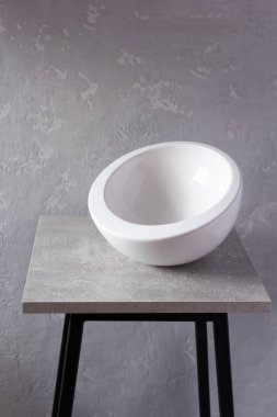 Boş beyaz kase ya da gri masa ya da taburede dishe. Mutfak bulaşık takımı ve sofra takımı duvar arkası dokusunun yanındaki rafta.