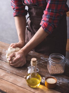 Fırıncı erkek el yoğurma veya hamur ve fırın malzemeleri masada ev yapımı ekmek pişirmek için. Duvar arkaplanı dokusu yakınında fırın kavramı