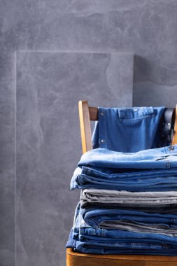 Kot pantolon ve ceket eski ahşap sandalyede, duvar arkası dokusunun yanında. Klasik kot pantolon modasının modern günlük tarzı