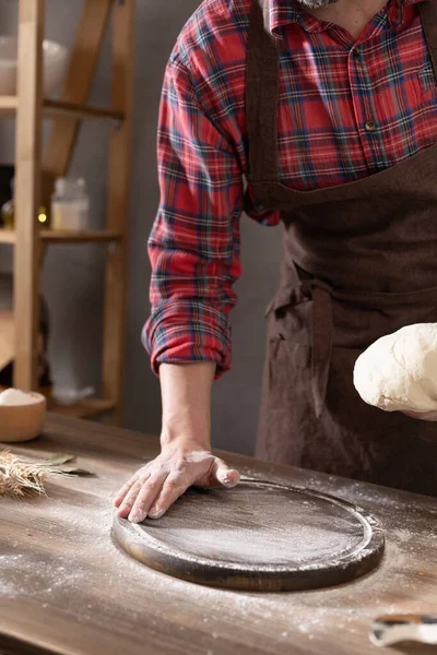 Fırıncı adam masada ev yapımı ekmek pişirmek için hamur ve fırın malzemeleri yapıyor. Fırın konsepti ve erkek eli