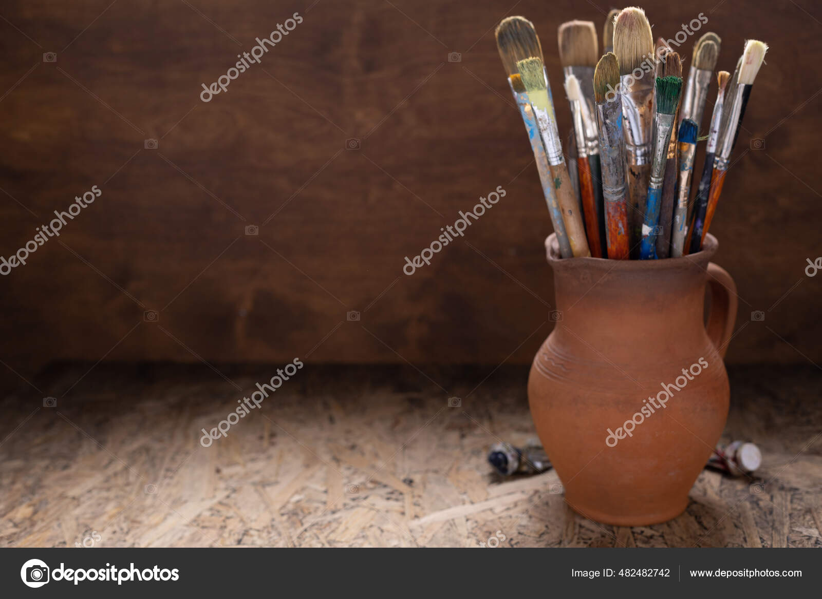 Paint brush in clay jug and palette on wooden table background. Oil painting  and art still life Stock Photo by seregam