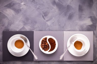 Masada bir fincan kahve. Tabakta kahve çekirdekleri ve soyut arkaplan dokusunda kahve fincanı