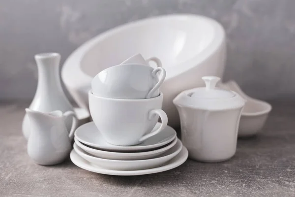 空陶器套装或白色陶瓷盘 厨房的白色餐具和桌面上的餐具接近灰墙背景纹理 — 图库照片