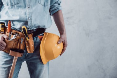 İnşaat miğferi tutan işçi beton ya da beton duvarın yanında. Ev dekorasyonu için erkek eli ve sert şapka. Ev yenileme konsepti