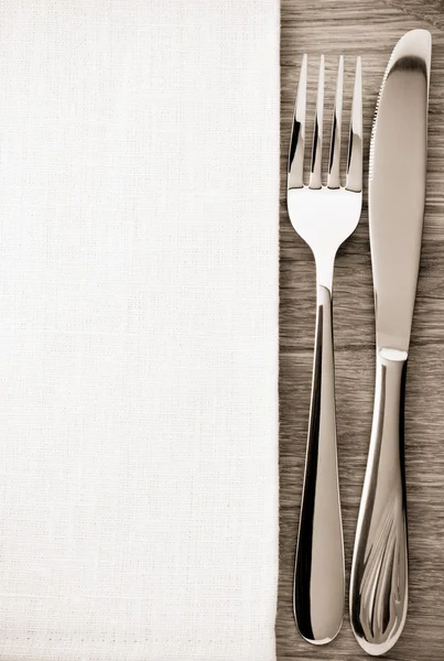 Cuchillo y tenedor en la servilleta en madera — Foto de Stock