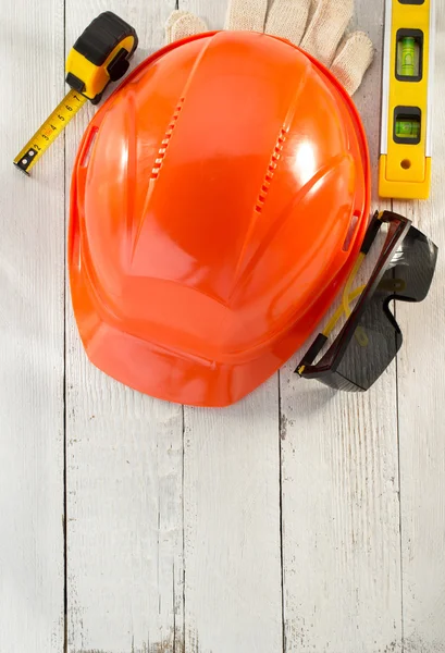 Hardhat and safety glasses on wood — Stock Photo, Image