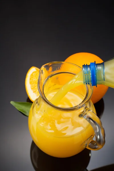 Jarro de vidro e suco de laranja em preto — Fotografia de Stock