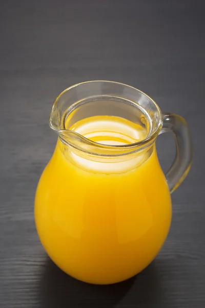 Jarro de vidro e suco de laranja na madeira — Fotografia de Stock