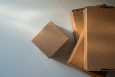 Temiz beyaz bir yüzeye birkaç tane kahverengi karton kargo kutusu. Yüksek Açı Görünümü