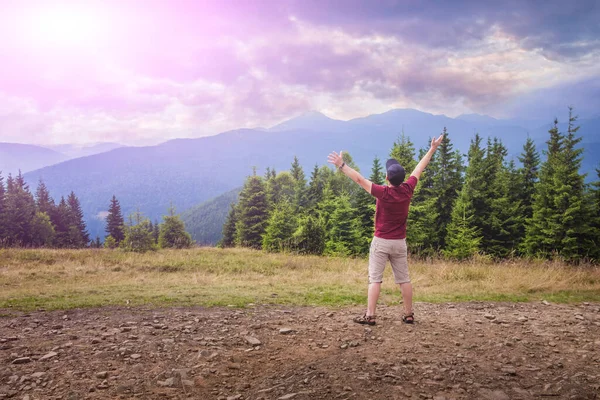 A man in the mountains with his arms raised up towards the morning sun. The man feels happy in nature among the mountains