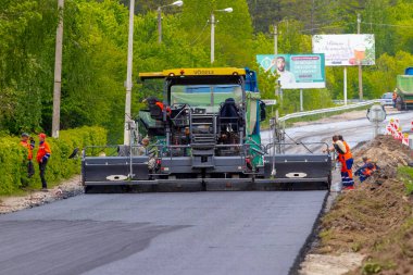 Ukrayna, Khmelnytsky bölgesi, Krasyliv. Mayıs 2021. Asfalt kaldırımı asfalt döşeme sırasında yolda. Yol tamiri. Yeni bir yol açıyorum