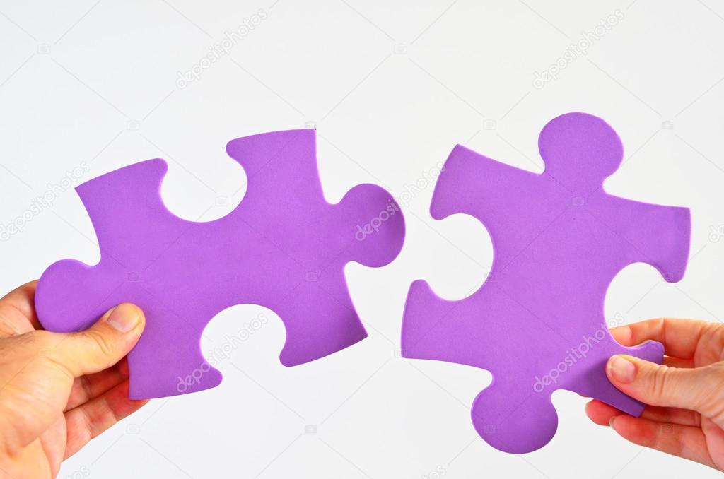 Man and woman hands holds two different puzzle pieces separated