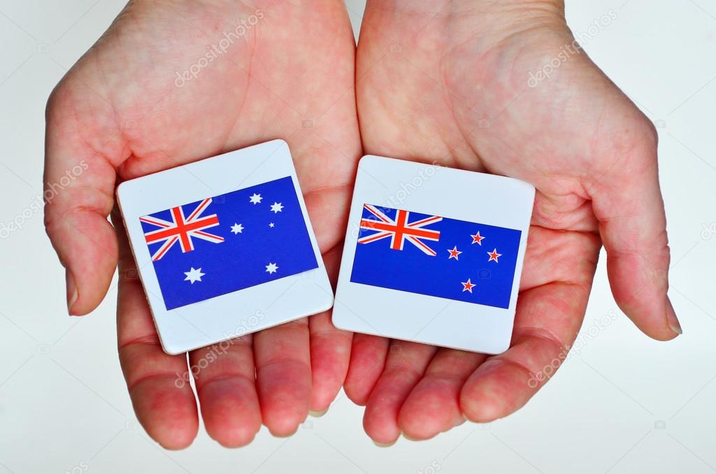 Two hands holds the national flags of Australia (R) and New Zeal