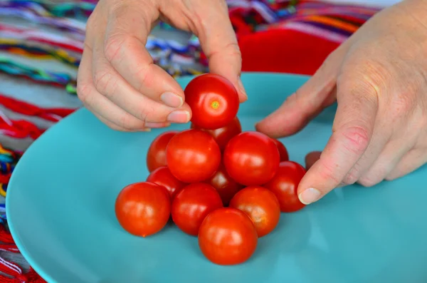 Woman hands arrange Cherry tomatoes in a plat — Stock Photo, Image