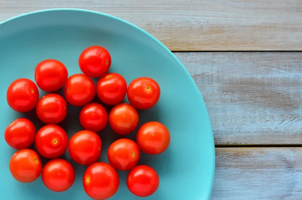 Puesta plana de tomates Cherry en un plato de color turquesa — Foto de Stock