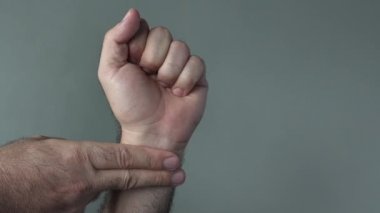 Adam ellerini denetler kendini gri bir arka plan üzerinde nabız