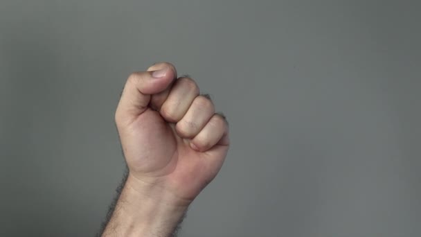 Hombre mano mostrar puño sobre un fondo gris — Vídeo de stock