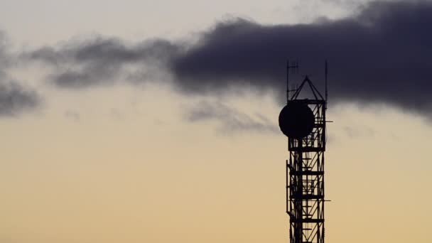 Silhouette de tour de communication avec antenne parabolique et antennes au lever du soleil 