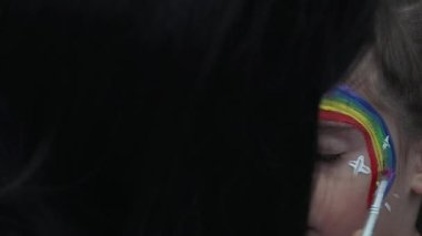 Küçük kızın yüzünü rainbow ile boyalı