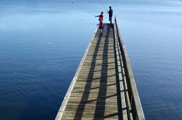 Papai e duas crianças pescando de um cais — Fotografia de Stock