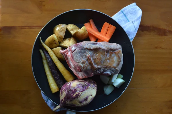 Flat lay of pice of a lamb meat fried with raw root vegetables i — Stock Photo, Image