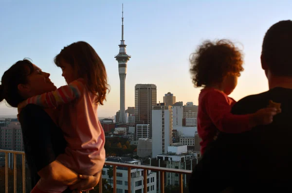 Pareja con dos hijos mira el horizonte de la ciudad al amanecer — Foto de Stock