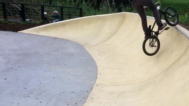 Freestyle BMX syklit ratsastaja suorittaa hypätä perustuva temppu kaupunkipyöräpuistossa — kuvapankkivideo