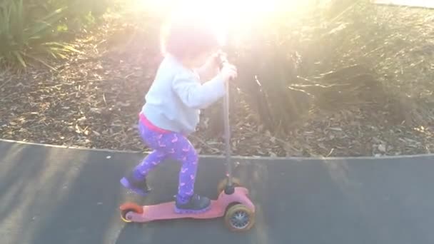 Медленное движение ребенка ездить на скутере в парке — стоковое видео