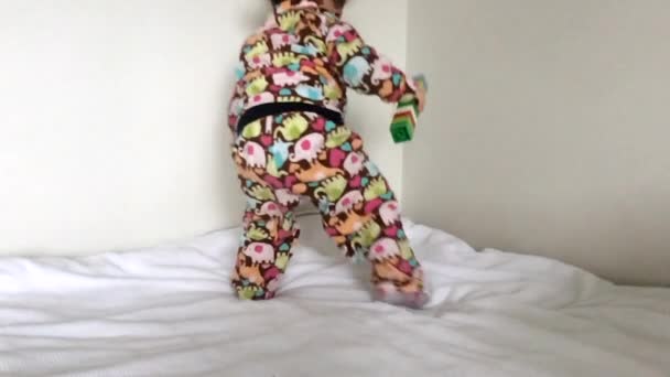 Cámara lenta feliz niña salta en una cama — Vídeos de Stock