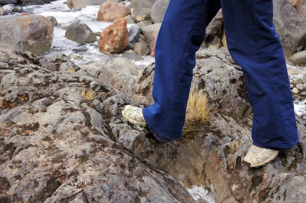 Legs of a woman hiker walks over rocks — Stock Photo, Image