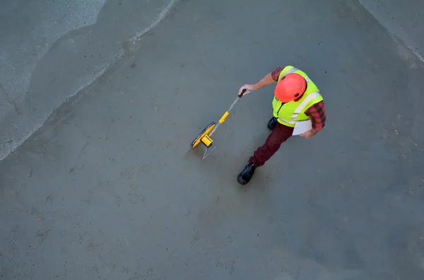 Foreman construtor de medição de piso de concreto com uma fita adesiva — Fotografia de Stock