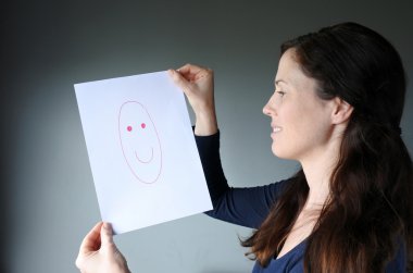 Young woman looks at a drawing with a happy face clipart