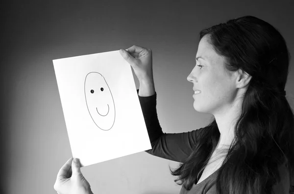 Young woman looks at a drawing with a happy face — Stock Photo, Image