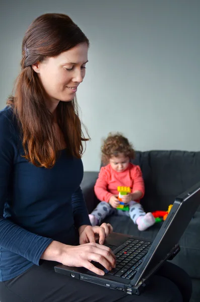 Glückliche Mutter mit Kleinkind arbeitet von zu Hause aus — Stockfoto