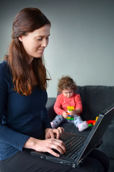 Mãe trabalha de casa em seu laptop — Fotografia de Stock