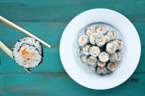 Fechar-se de pauzinhos mantém sushi maki gunkan rolo sobre uma chapa — Fotografia de Stock