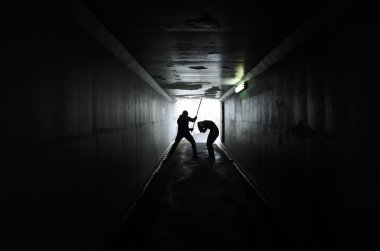 Bir adam bir kadının karanlık bir tünelde ahşap sopa ile yenerek silüeti. Kadın kavramı karşı şiddet. Gerçek insanlar, kopya alanı
