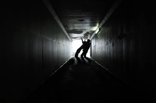 Silhueta Homem Ataca Uma Mulher Por Trás Num Túnel Escuro — Fotografia de Stock