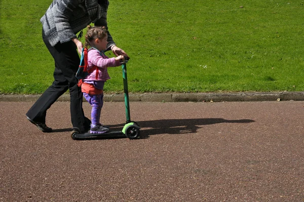 Moeder leert haar kind te rijden een scooter — Stockfoto