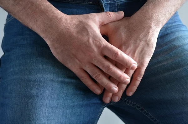 Мужские руки, прикрывающие его болезненную промежность — стоковое фото