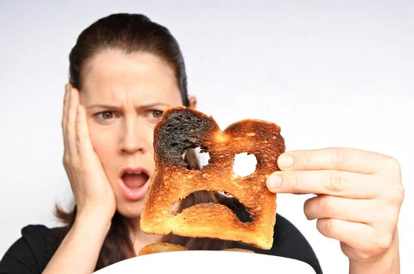 Schock-Frau hält verbranntes Toastbrot in der Hand — Stockfoto